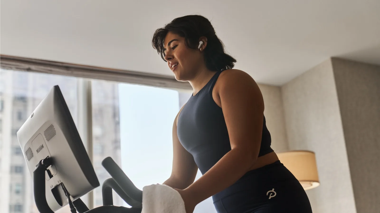 A woman on Peloton Bike Pro inside of a hotel room
