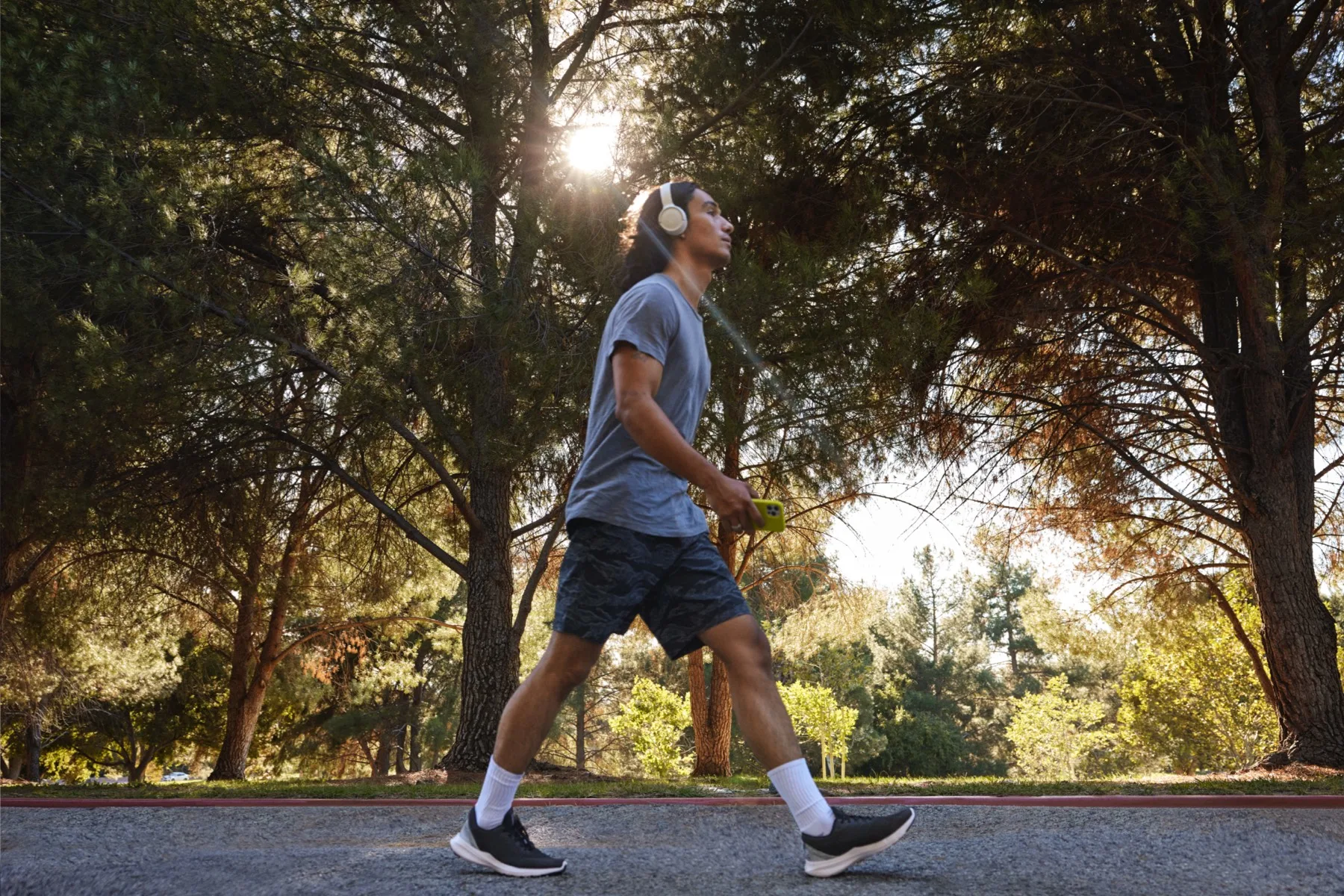 A person with headphones on walking on a path surrounded by trees