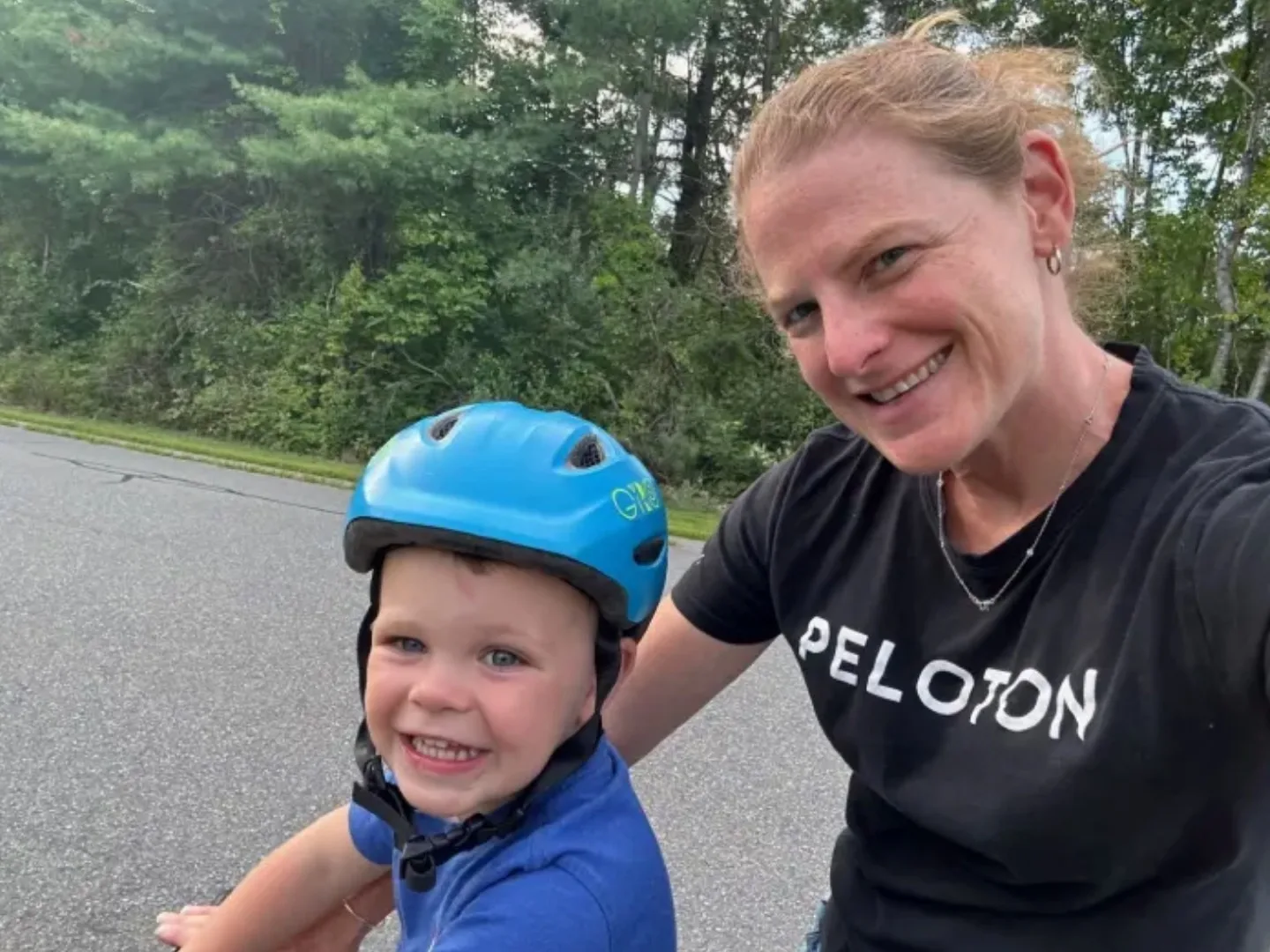 A Peloton Member smiling with a child on a bike