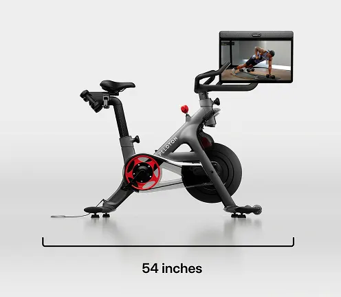 Peloton Bike+ with a large touchscreen display, red auto-resistance knob, and sleek black and gray frame