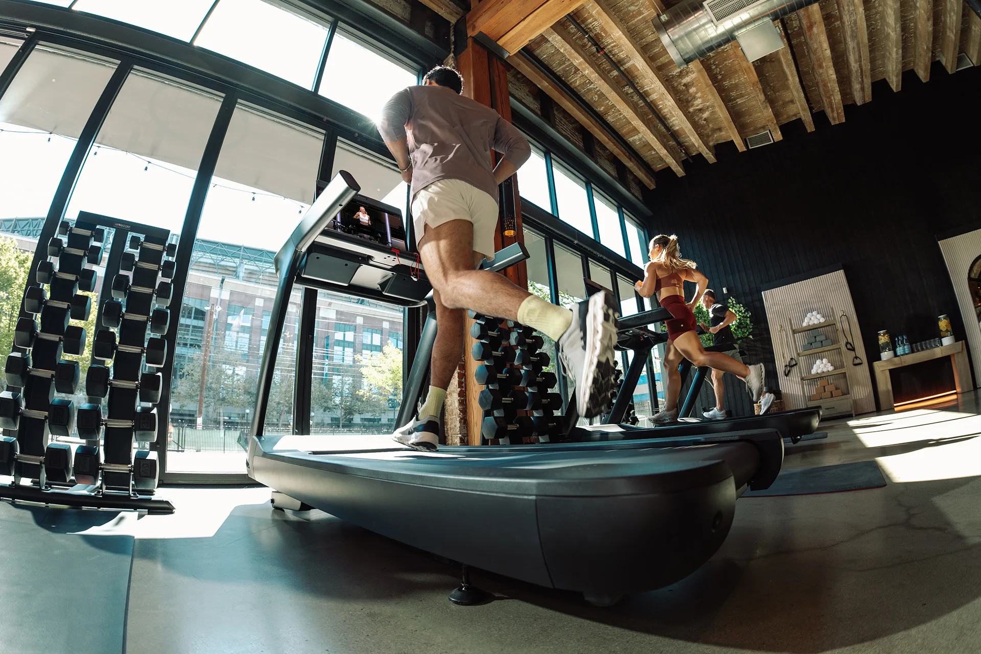 Three exercisers running on a Peloton Commercial Tread in a gym