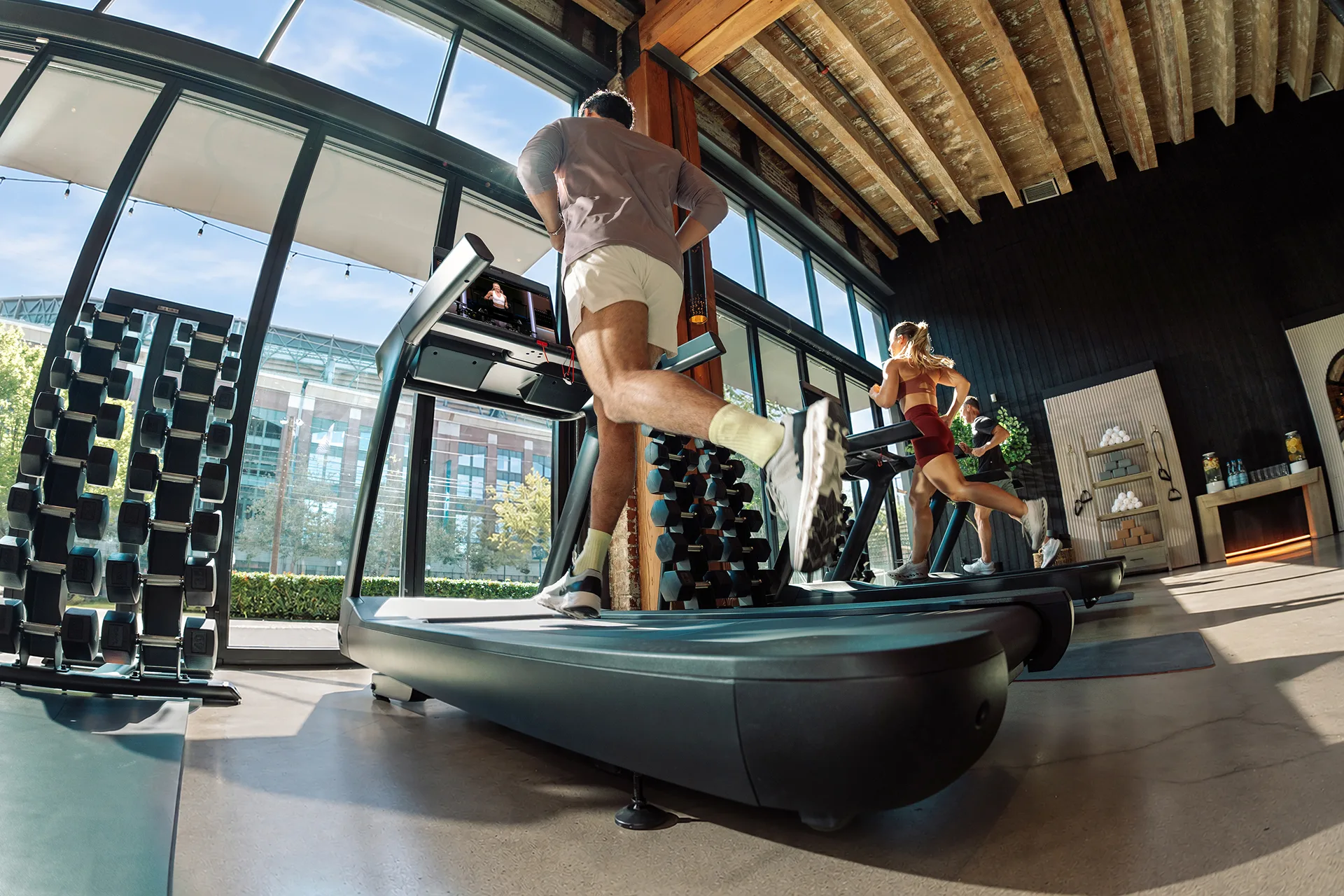 Three exercisers running on a Peloton Commercial Tread in a gym