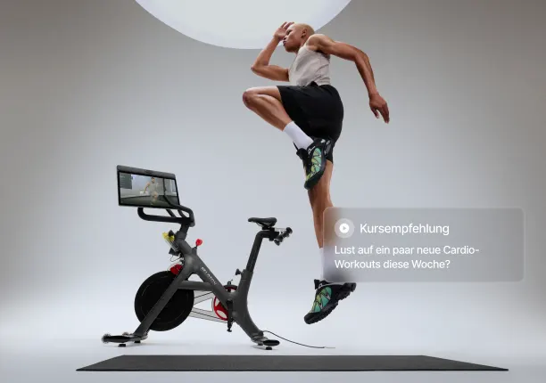 Eine Person trainiert neben dem Bike Pro und springt in die Luft. Ein Overlay blendet folgenden Text ein: „Kurs-Empfehlung: Lass uns diese Woche deine Cardio-Workouts erkunden!“
