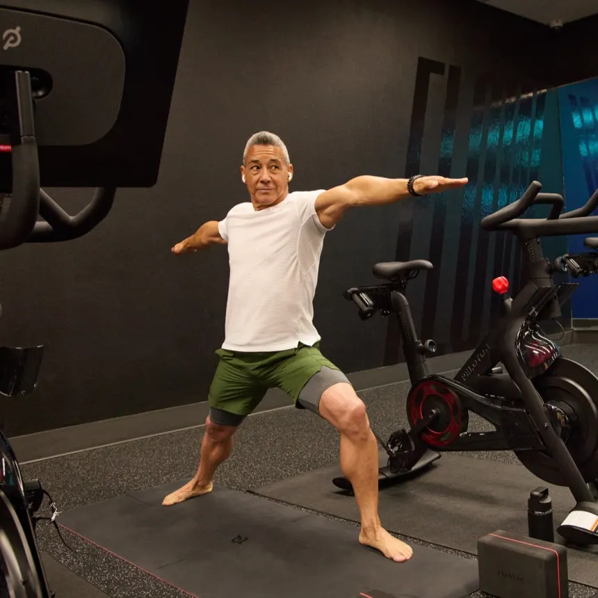 An exerciser using a cross-functional Peloton Bike for a strength class