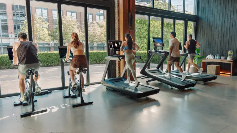 Four people working out on Peloton Commercial Bikes and Treads in a gym