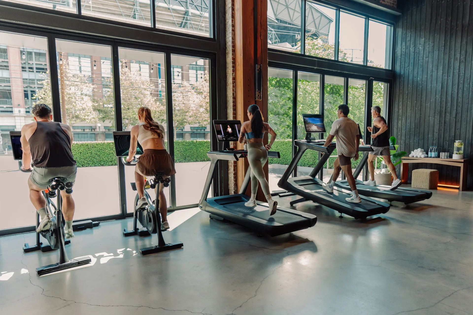 Four people working out on Peloton Commercial Bikes and Treads in a gym