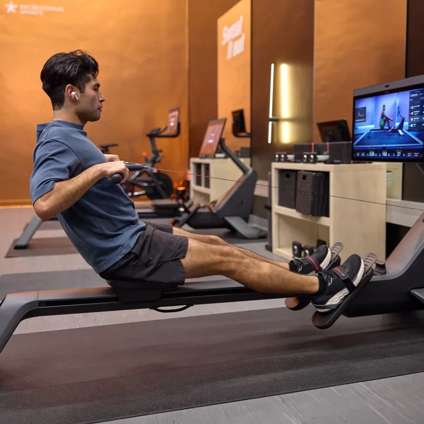 An exerciser using a Peloton Row in a Peloton branded gym
