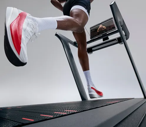 Rear view of a person walking on the Peloton Tread+ with the motor turned off for a self-powered workout.