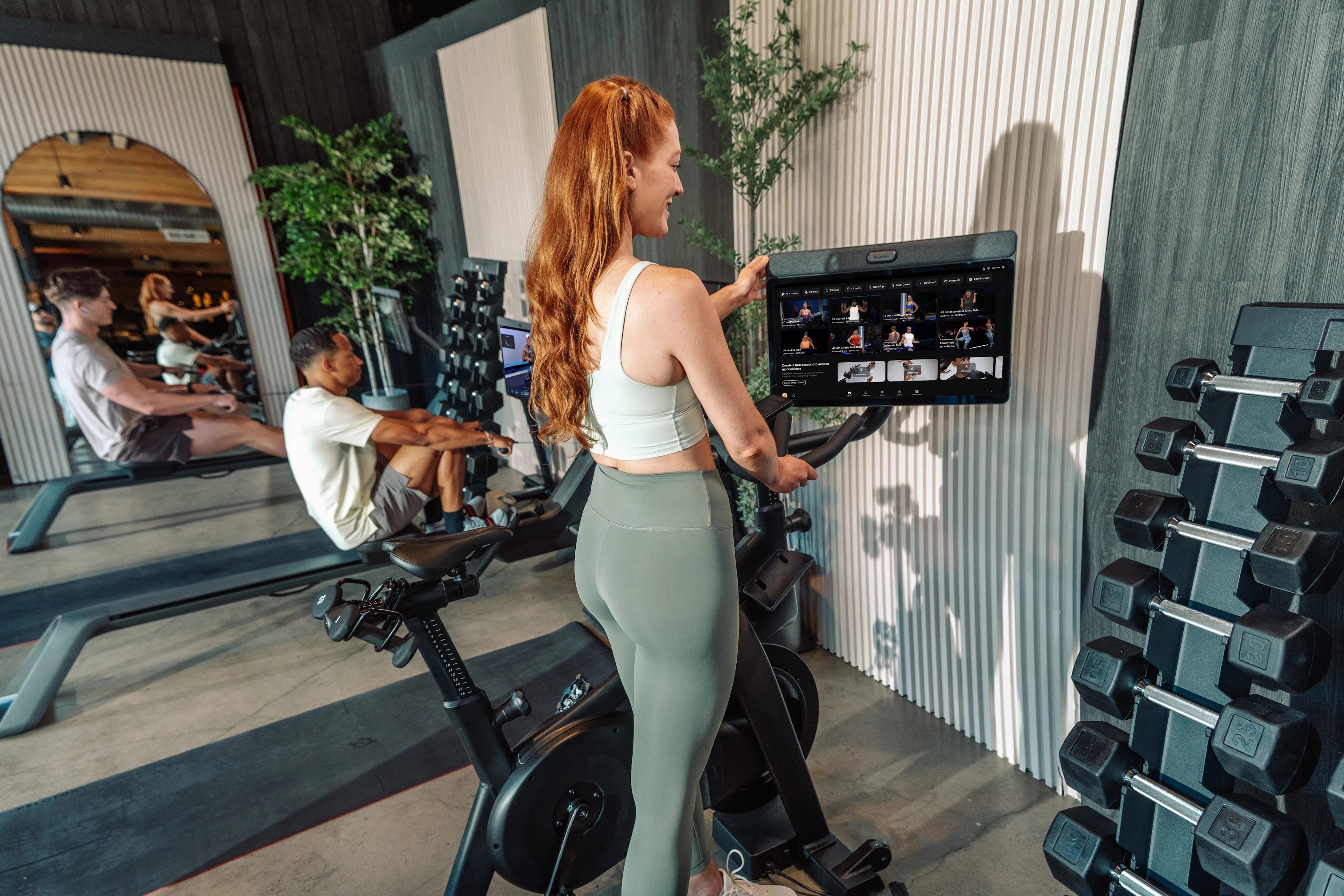 Eine Person steht neben einem professionellen Heimtrainer und tippt auf den Touchscreen.