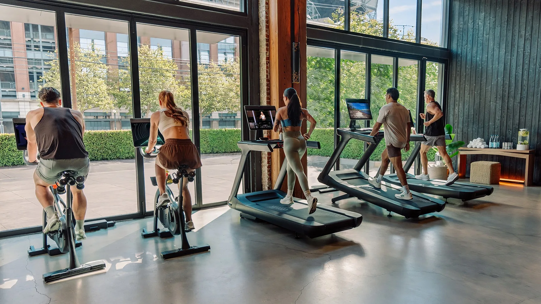 Vier Personen trainieren in einem Fitnessstudio auf Peloton Commercial Bikes und Treads.