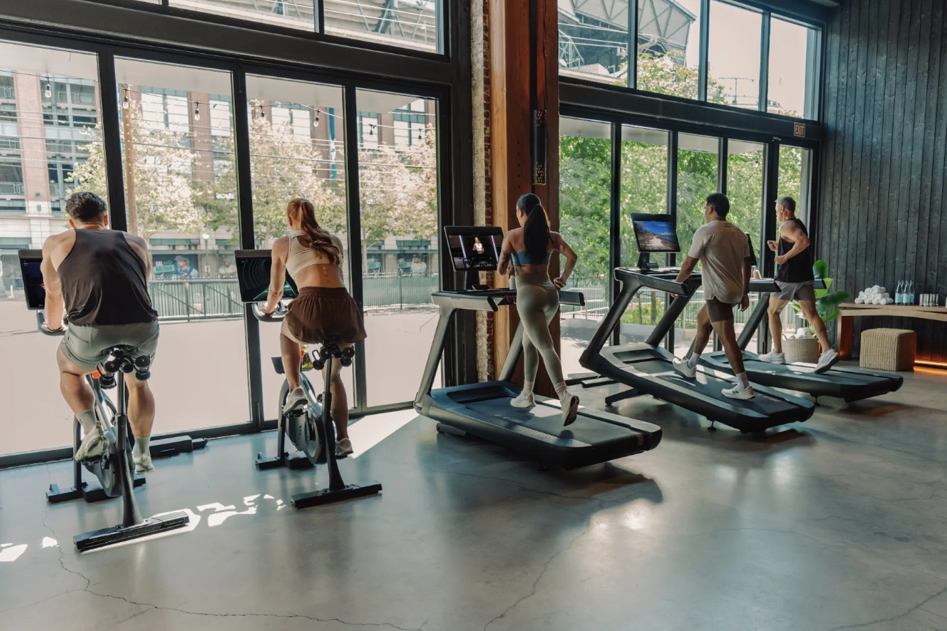 Four people working out on Peloton Commercial Bikes and Treads in a gym
