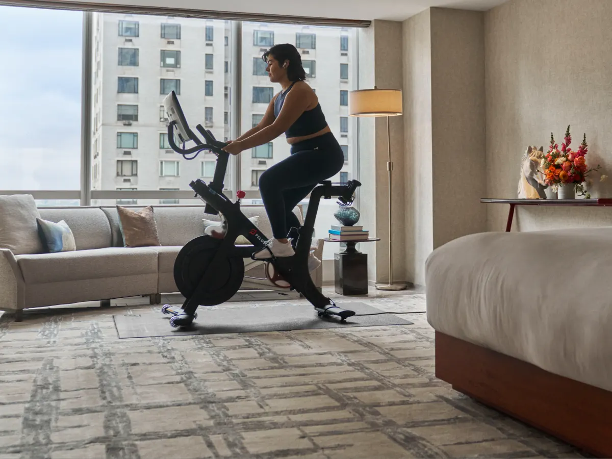 A woman working out inside her hotel room on a Peloton Bike Pro.