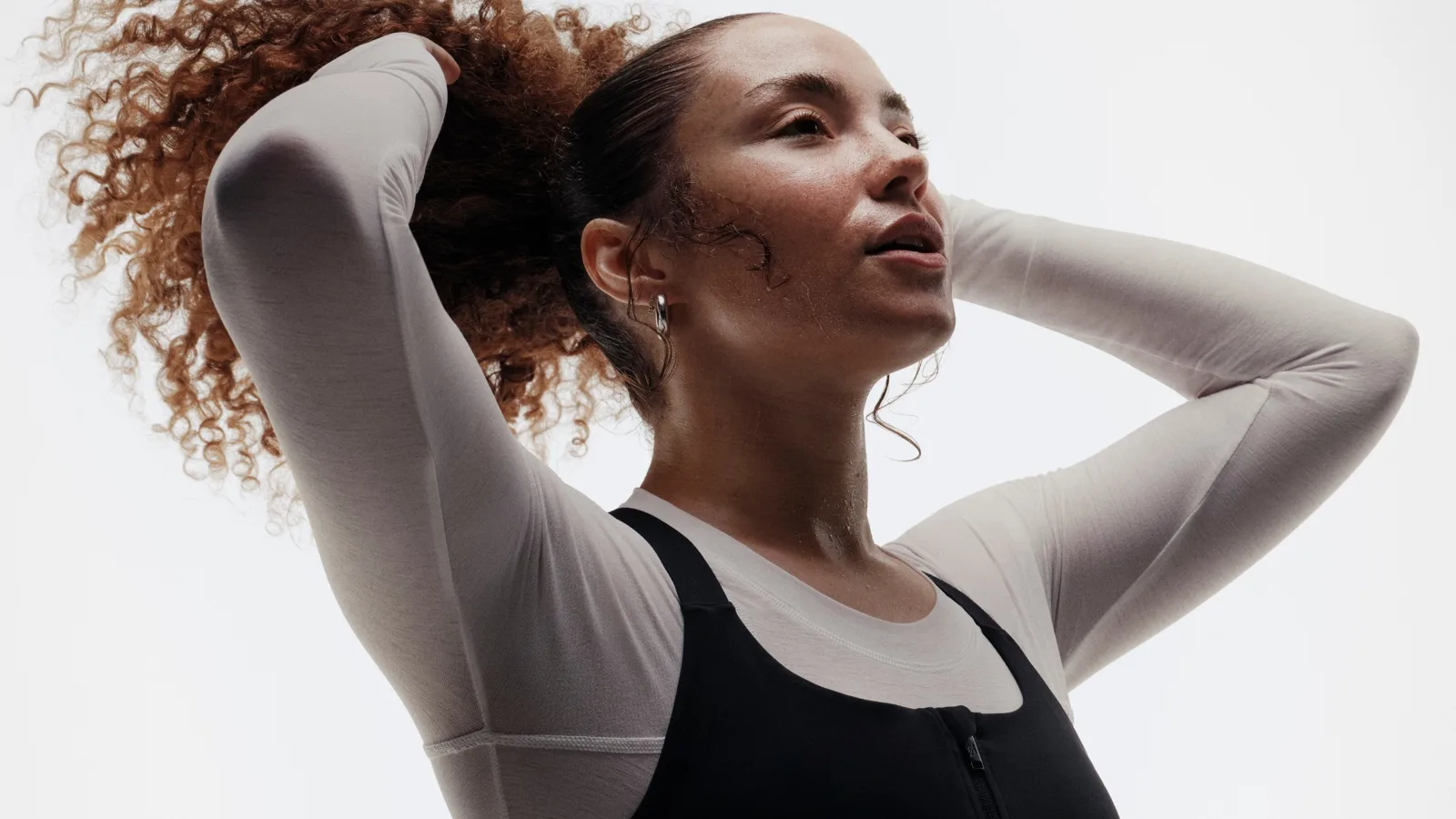 A woman adjusting her hair and cooling down after a workout.