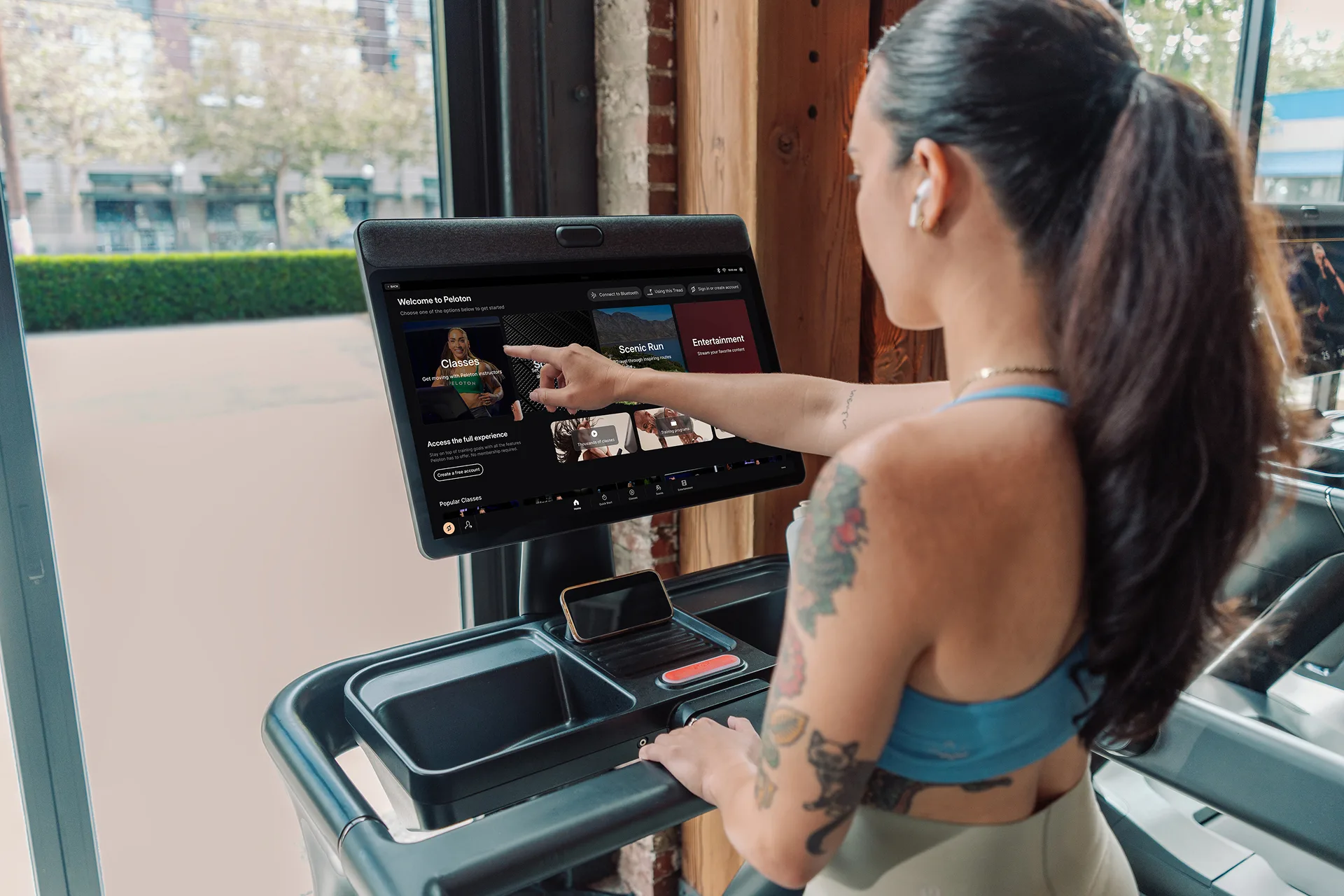 An exerciser interacting with the screen of the Peloton Commercial Tread