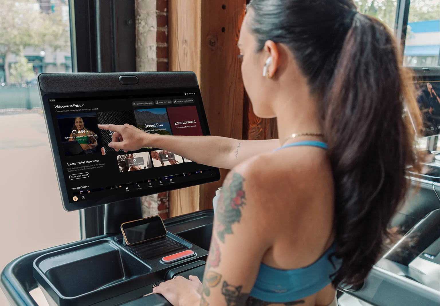 An exerciser interacting with the screen of the Peloton Commercial Tread