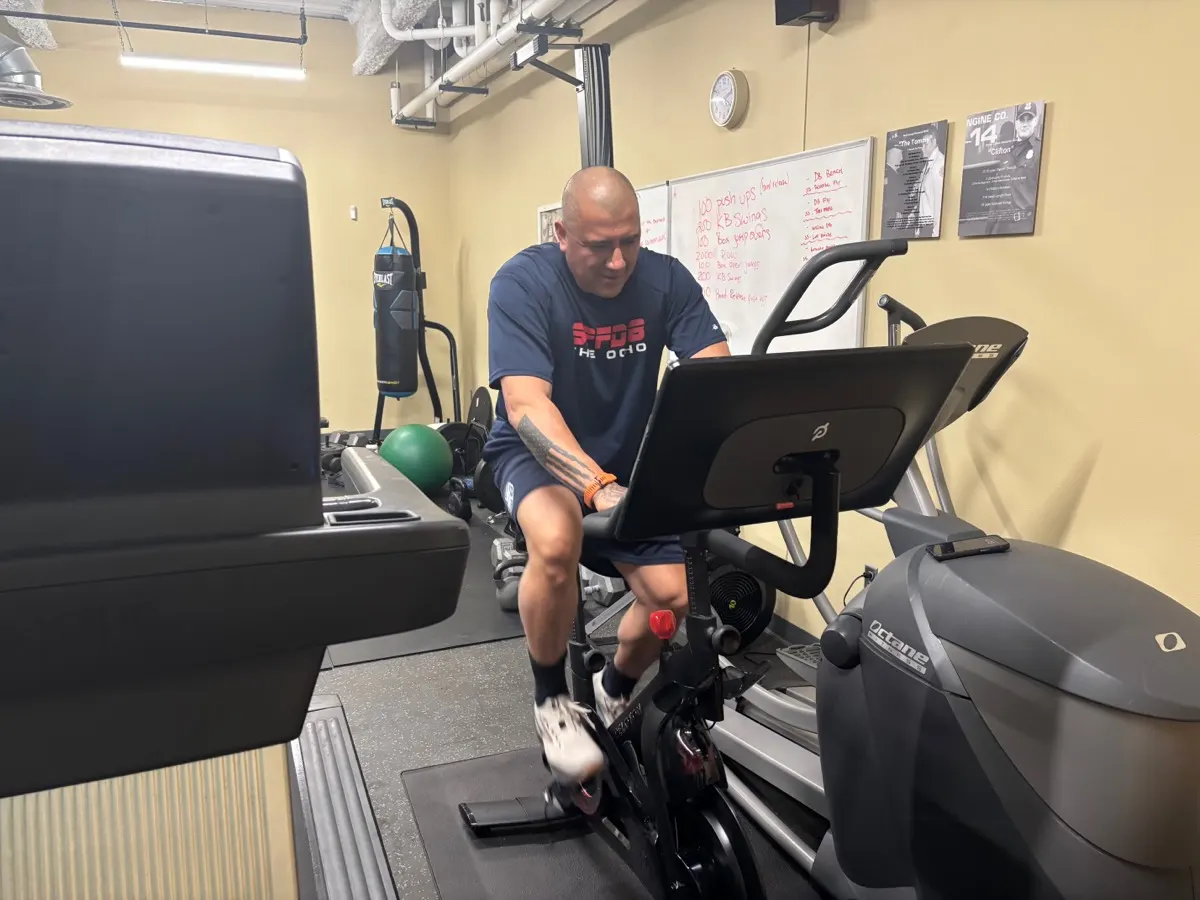 A firefighter exercising on a Peloton Bike