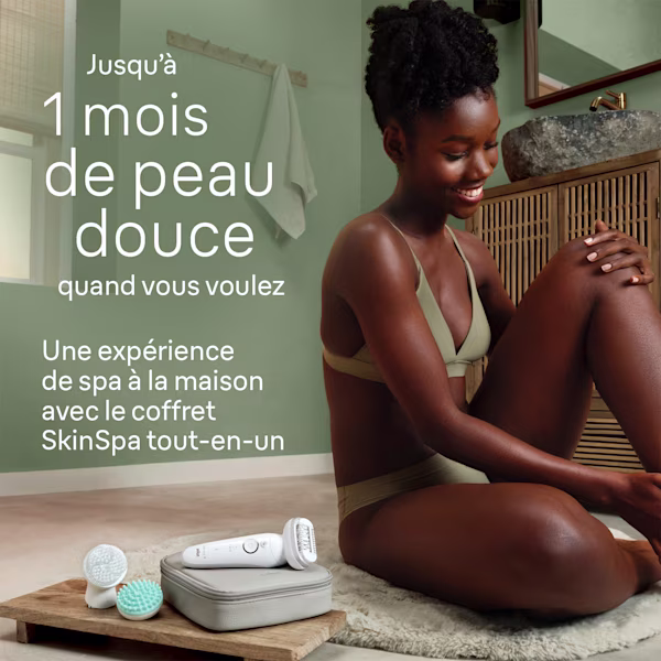 Femme souriante assise dans la salle de bains, appareil d’épilation à côté d’elle Femme souriante assise dans la salle de bains, appareil d’épilation à côté d’elle
