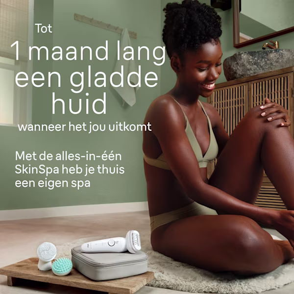 Vrouw die in de badkamer zit en lacht, met het epileerapparaat naast haar Vrouw die in de badkamer zit en lacht, met het epileerapparaat naast haar
