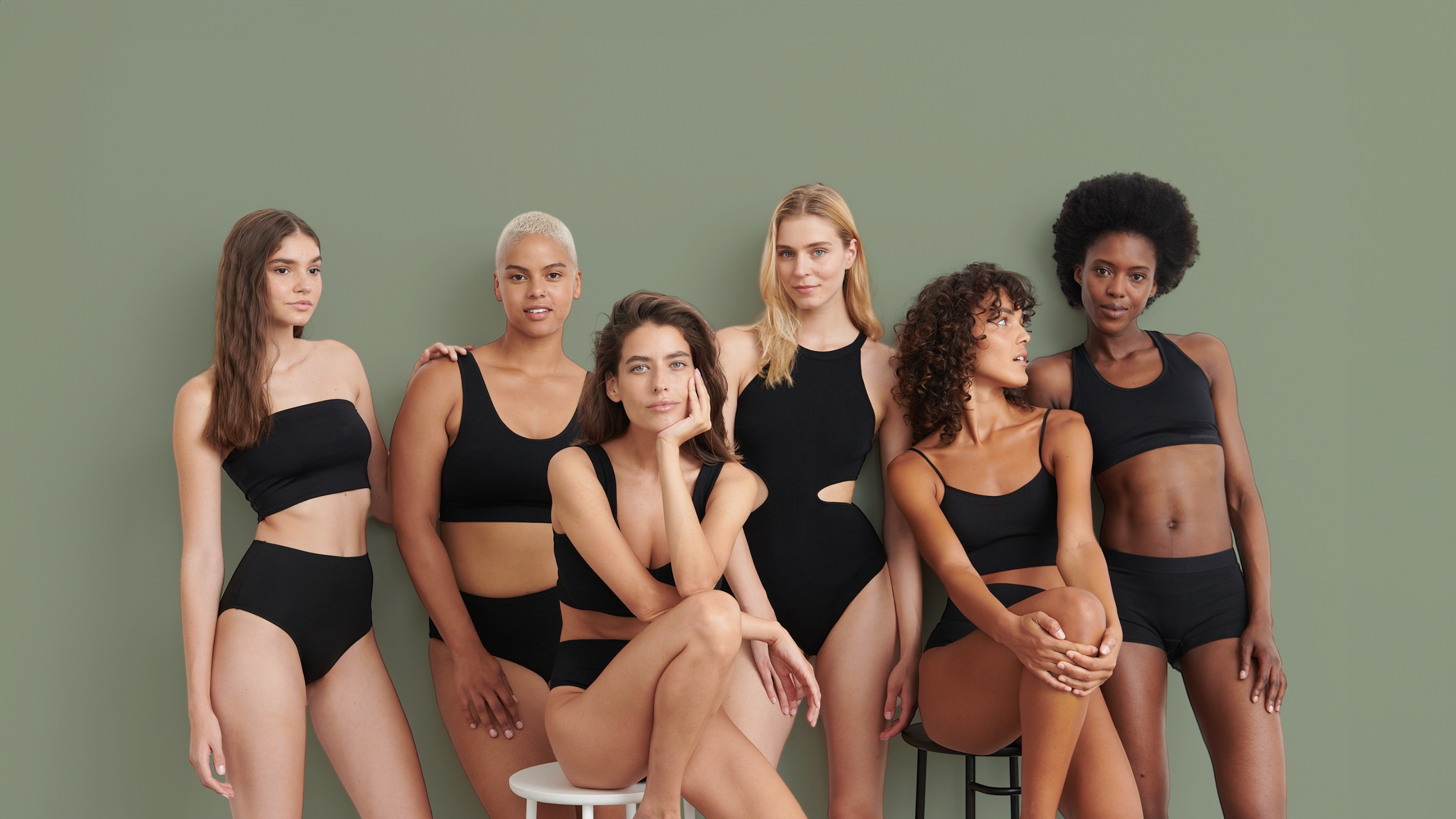 Groupe de 6 femmes portant des maillots de bain de sport noirs, assises et debout.