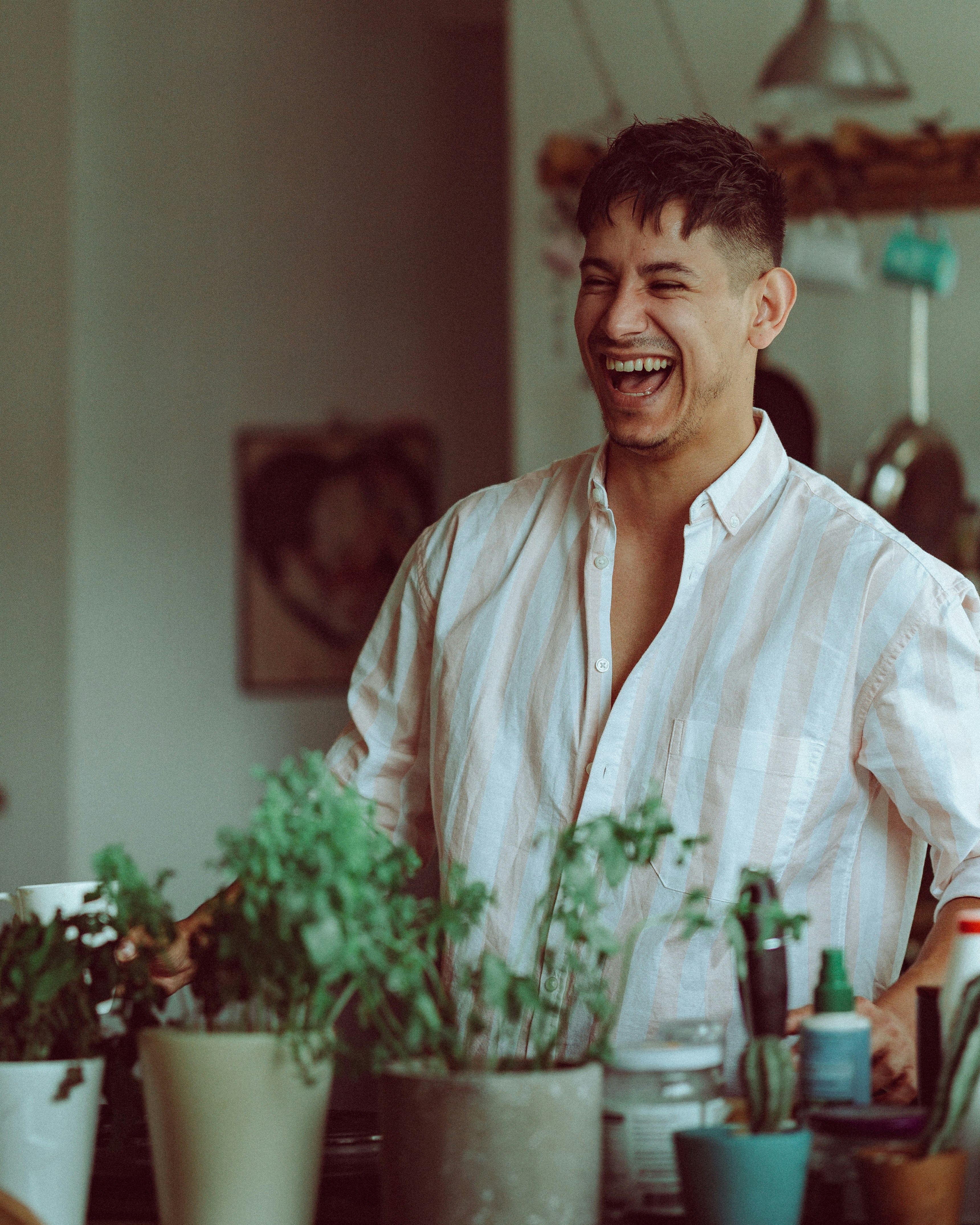 man in kitchen or bar with green plants herbs laughing