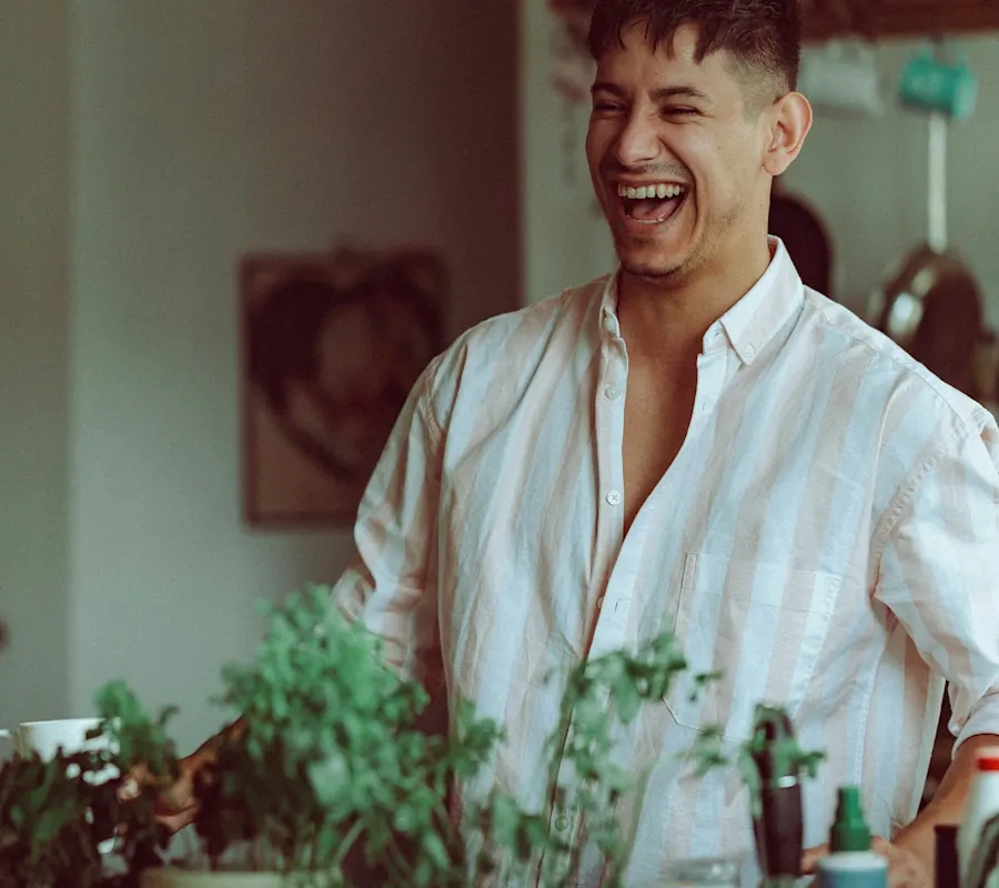 small man in kitchen or bar with green plants herbs laughing
