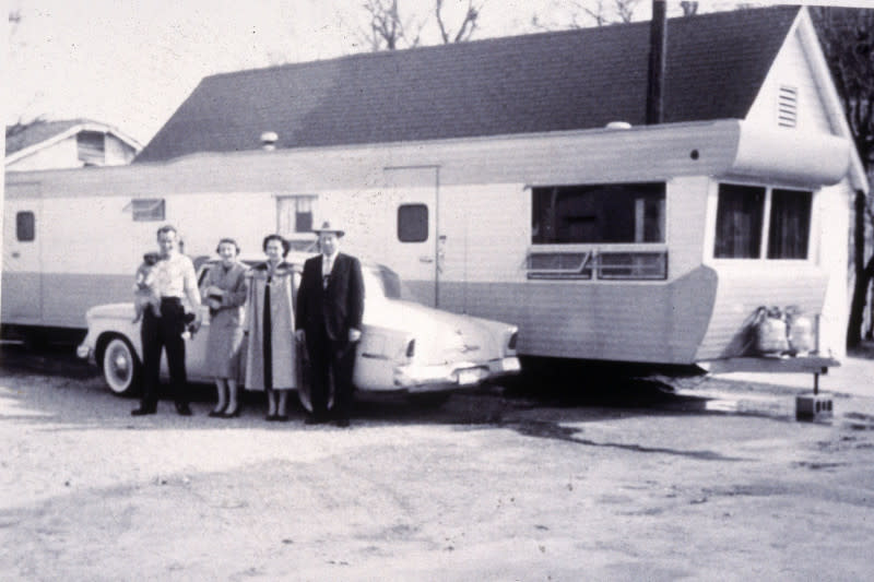 A black and white photo of a family standing in front of a mobile/manufactured home of the past. 