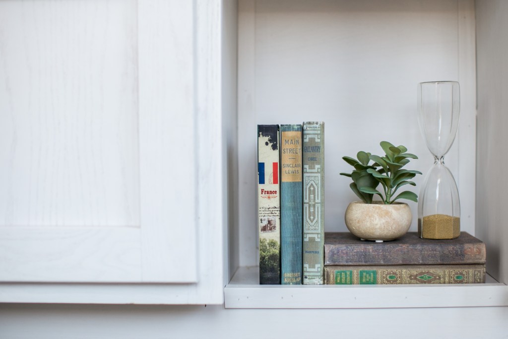 Books, a planter with plant, and an hour glass in view. 