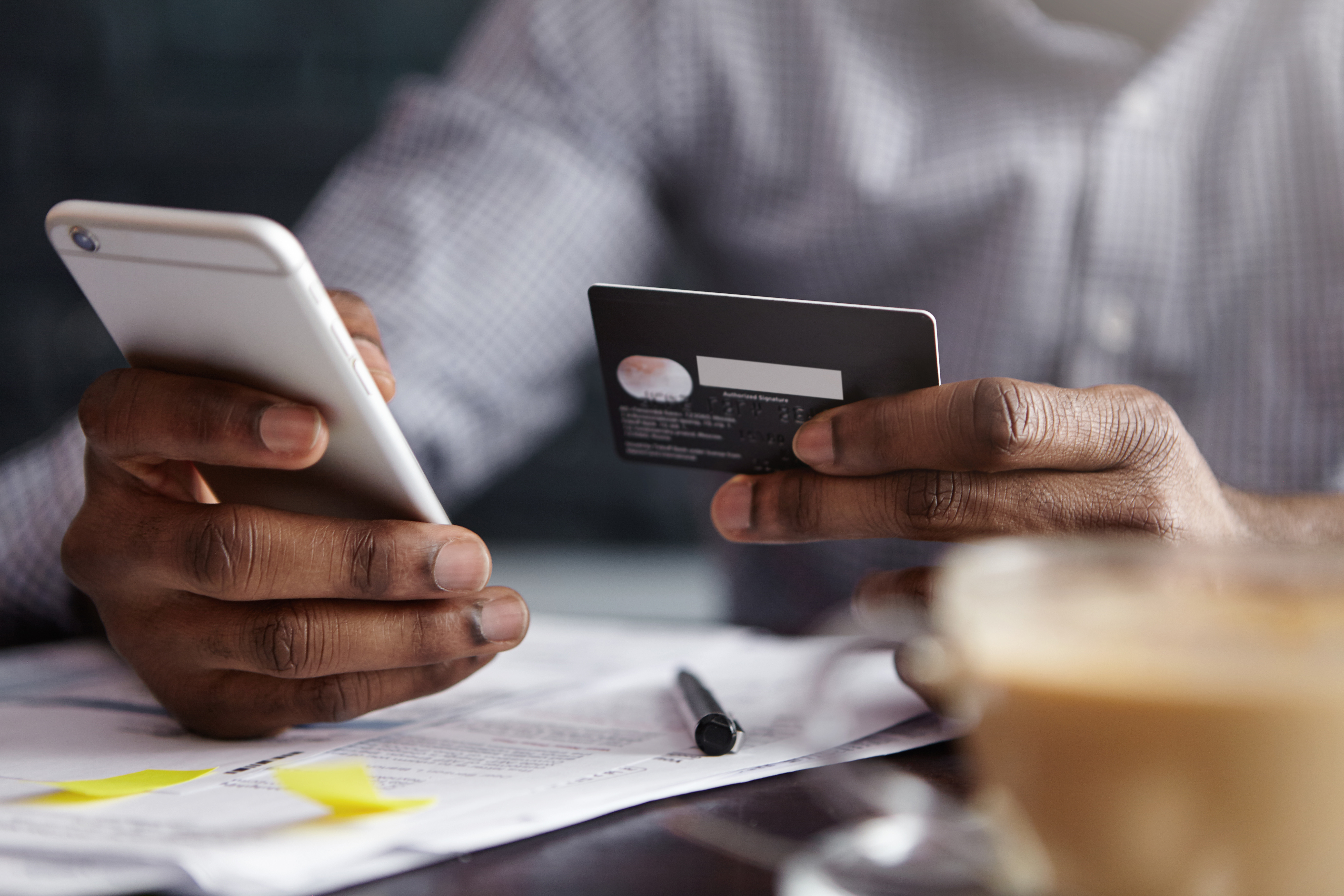 person's hands holding a smart phone and credit card