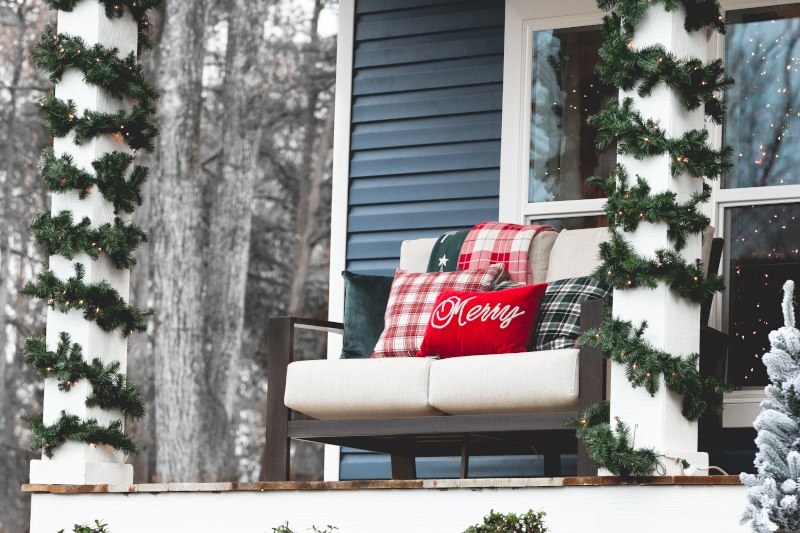 Blue home exterior with Christmas lights and décor on white bench