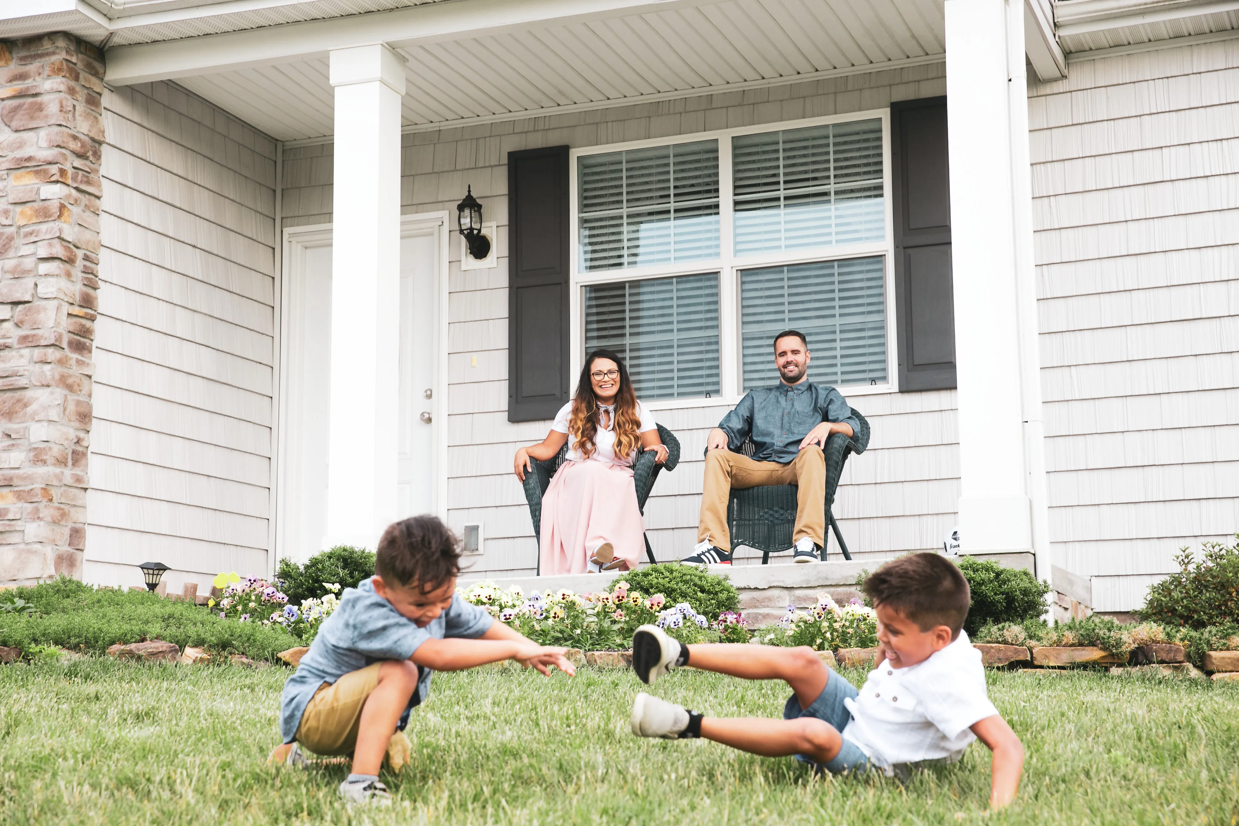 A couple sits on the porch of their manufactured home while watching their two sons play in the yard.