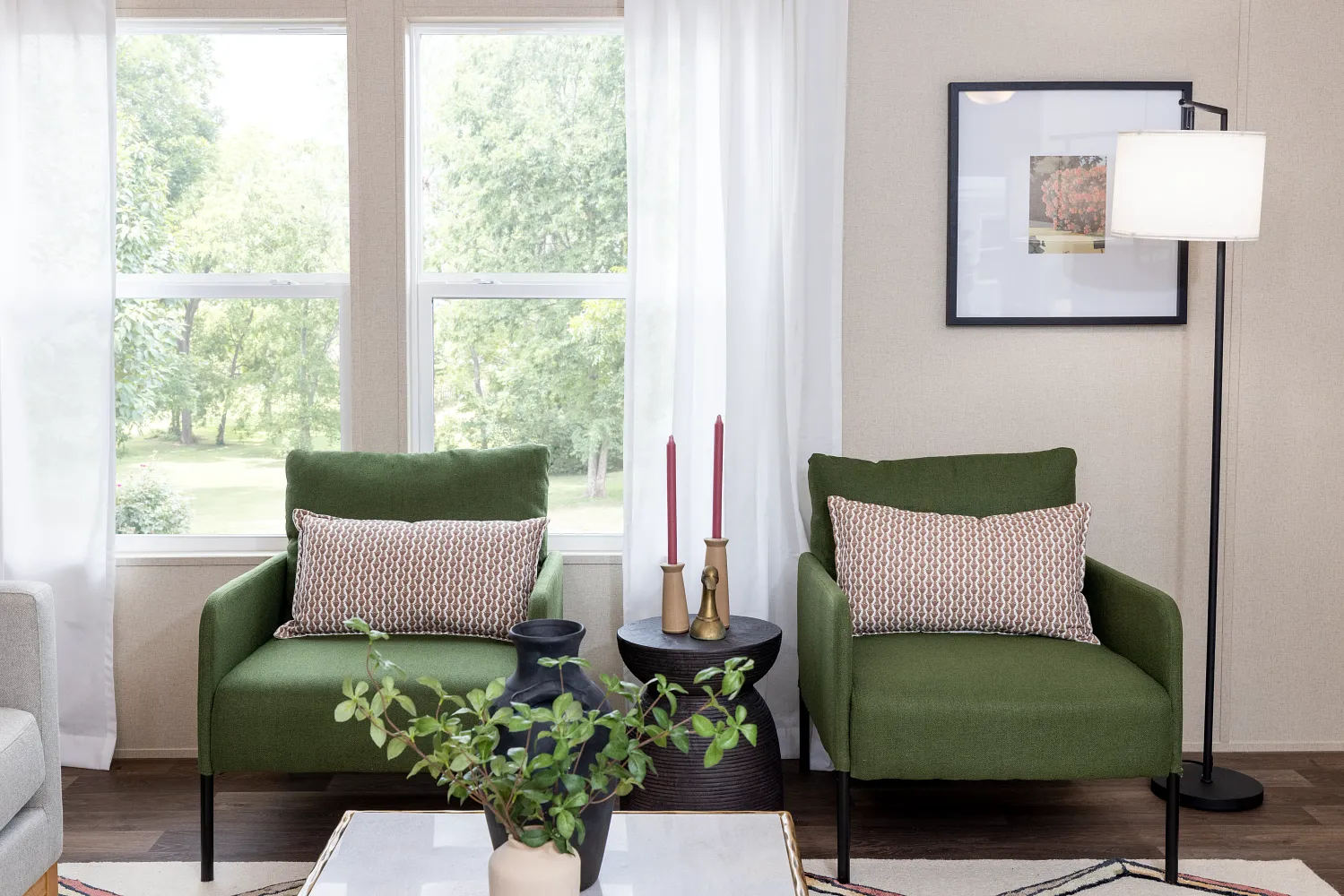 Living room with curtains and dark green chairs in front of it 