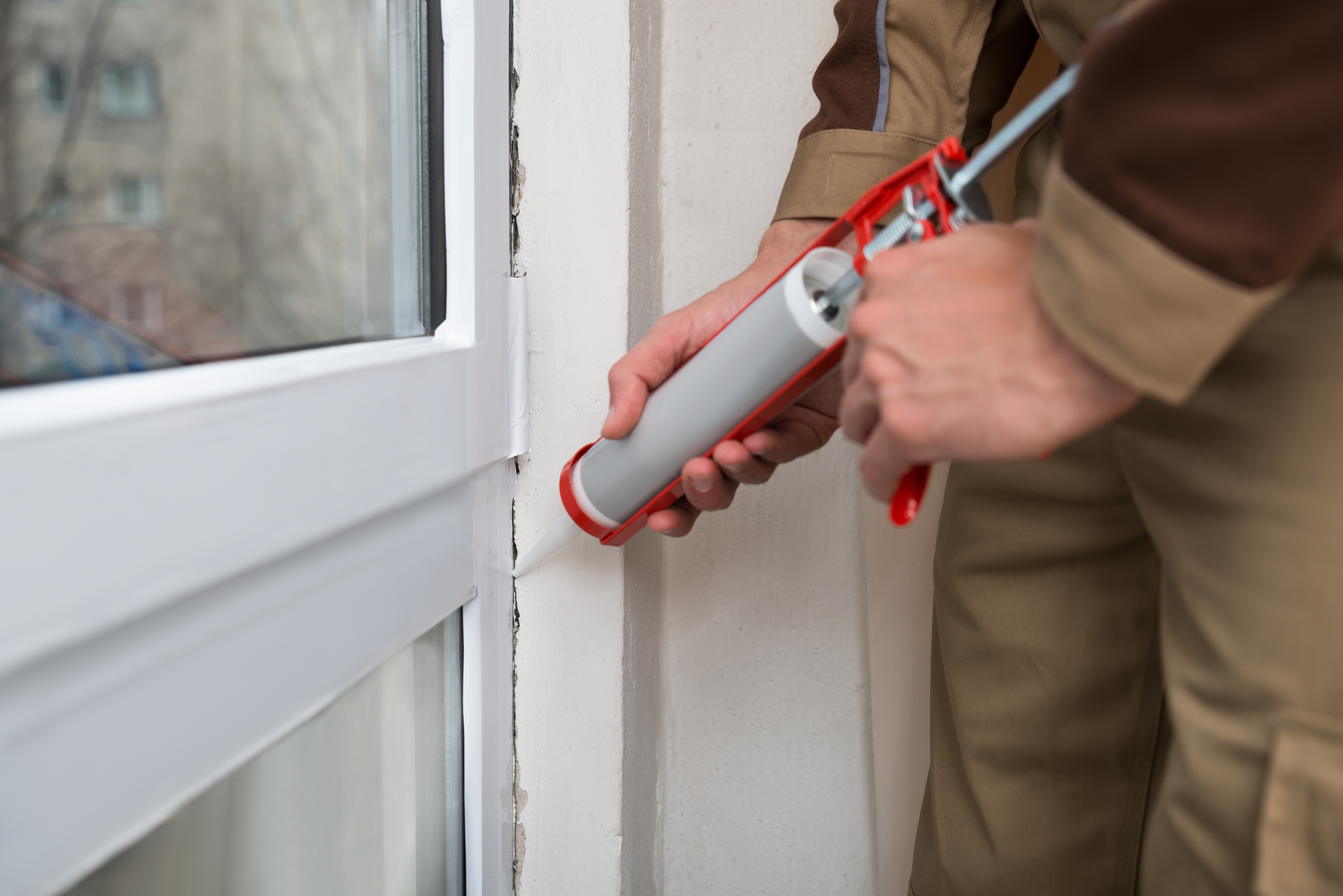 person using a caulk gun on a window 