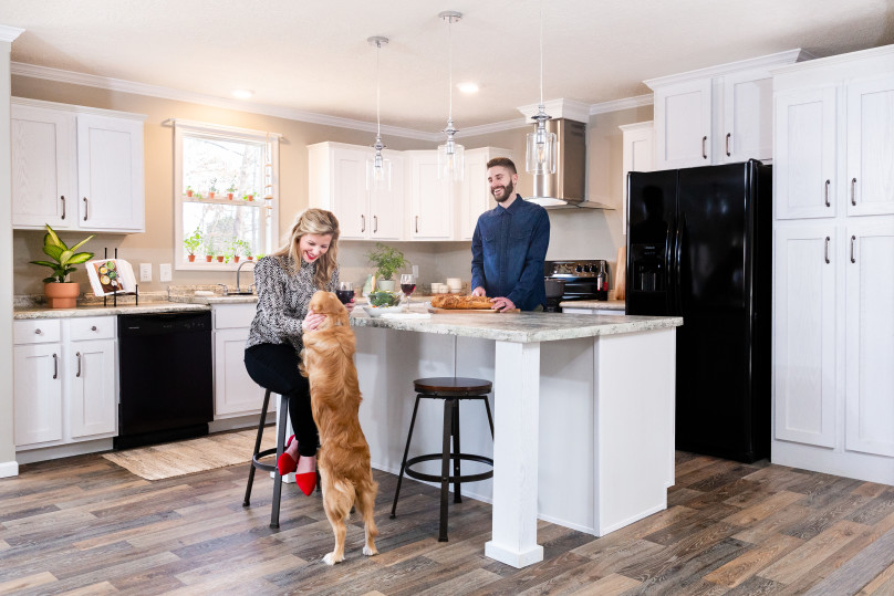 A couple and their dog enjoy dinner at their kitchen island.