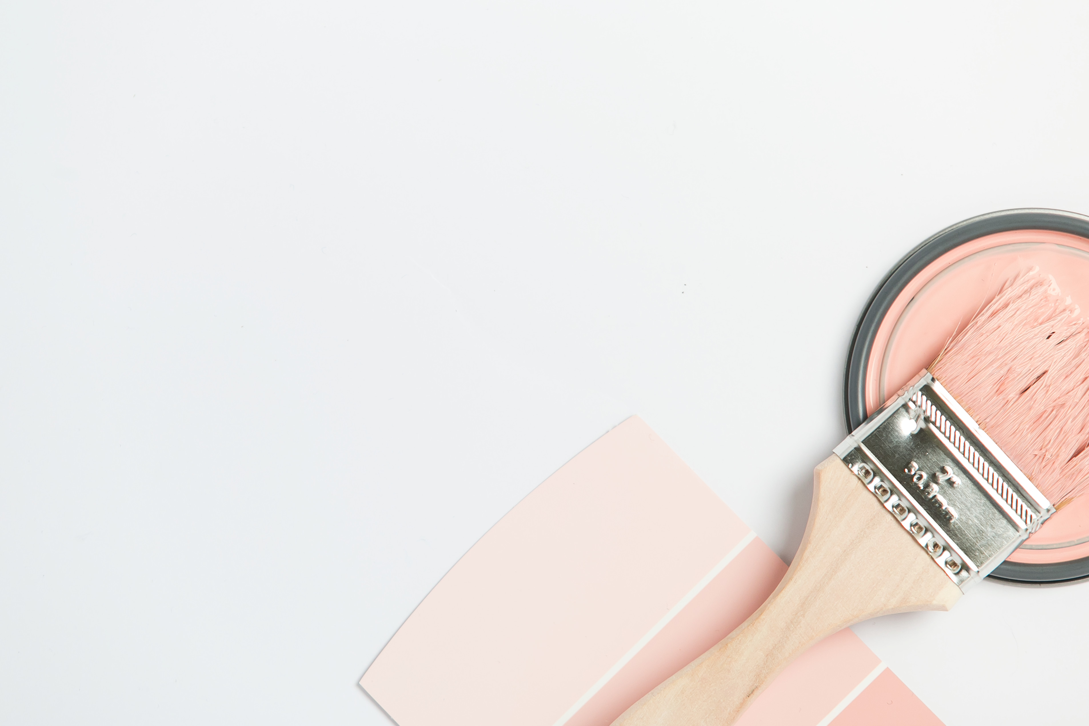 Flat lay of pink paint swatch with a paintbrush full of paint resting on a can lid