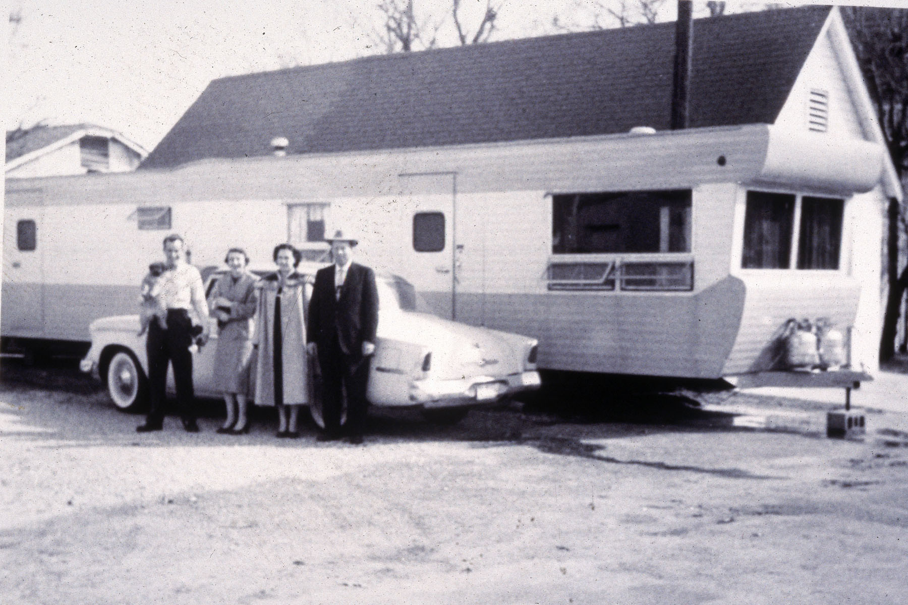 old mobile home with family and car in front of it 