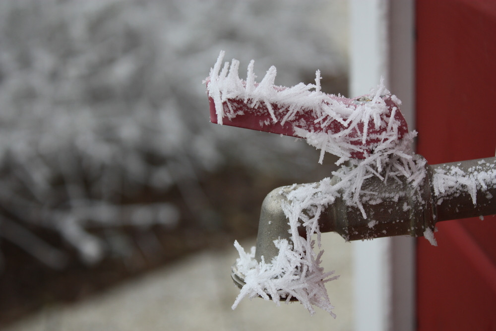 outdoor water spigot with ice cycles on it 