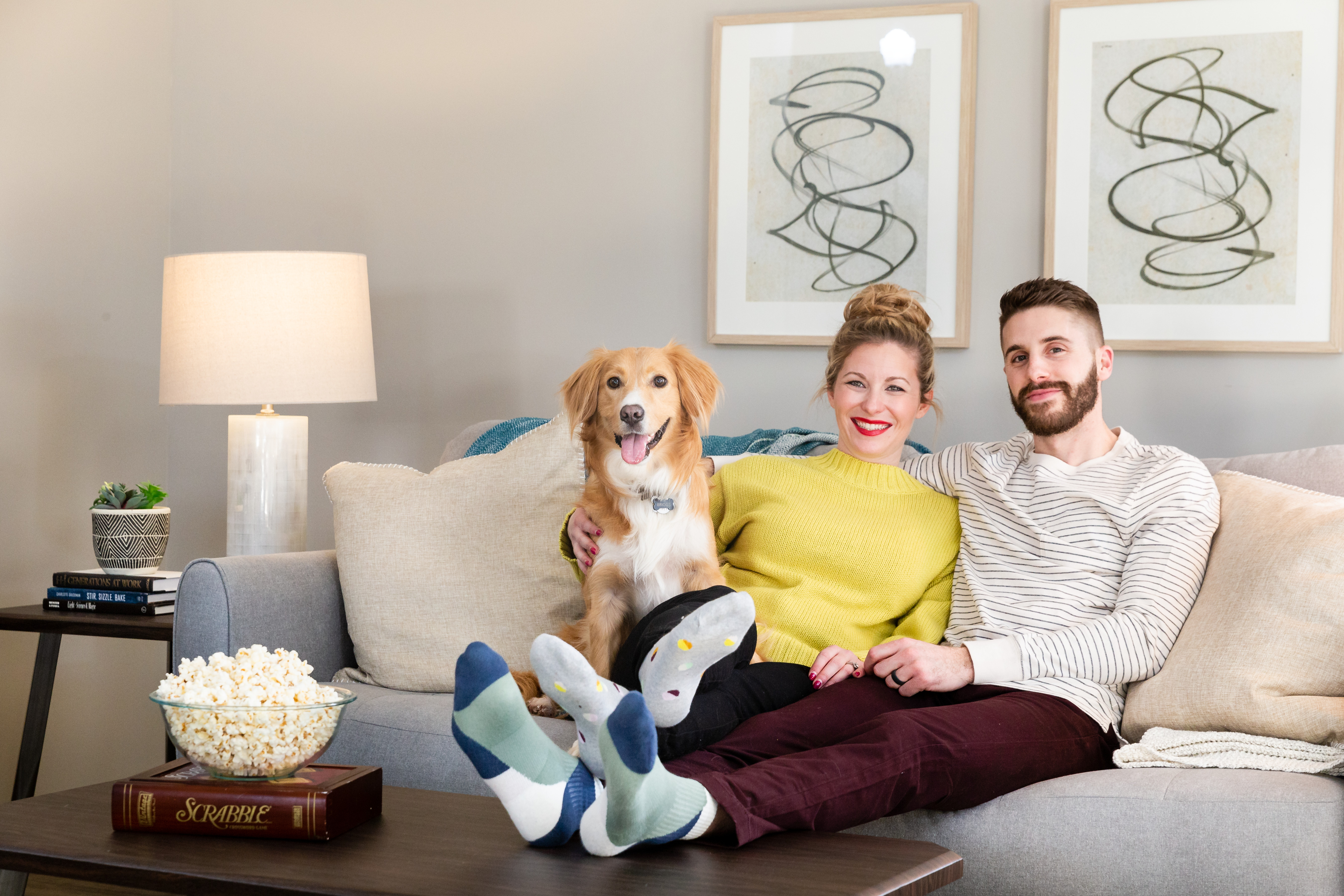 couple sitting on couch with dog and popcorn to the side