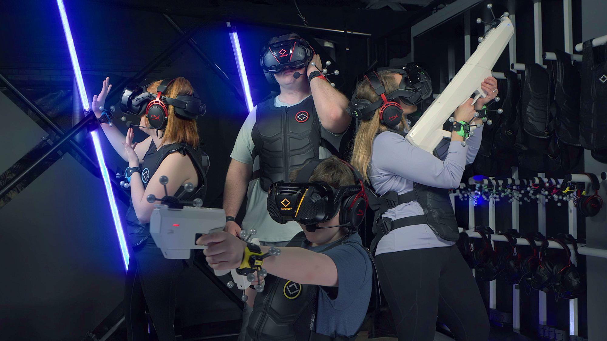 Gruppe mit VR-Headsets mitten im Spiel, beleuchtet von Neonlicht