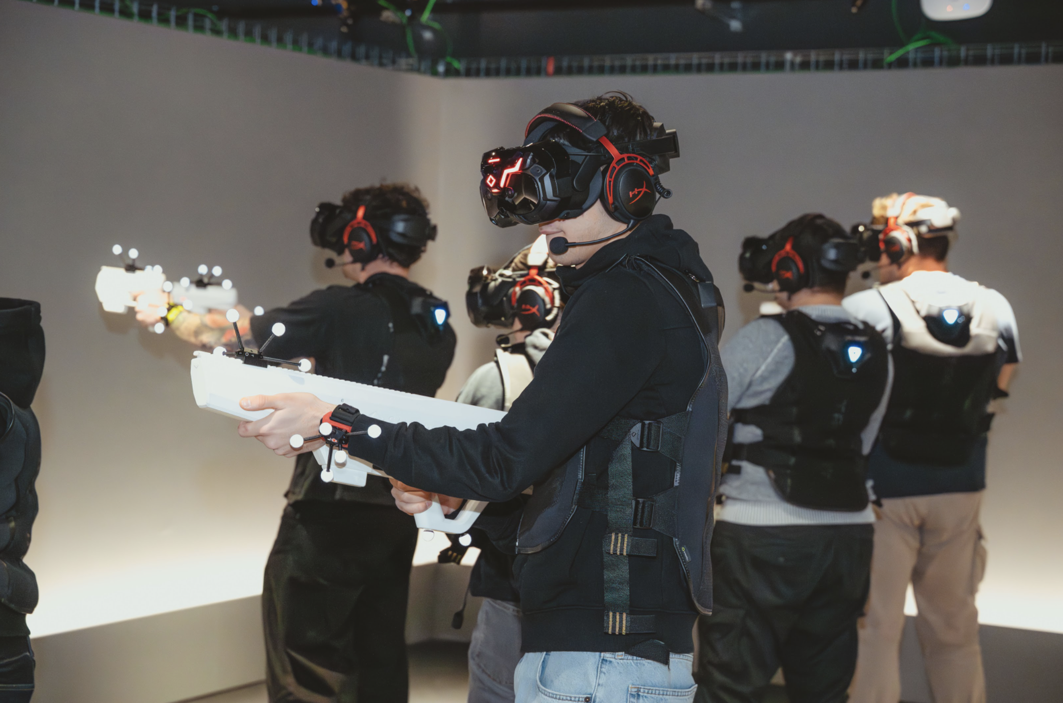 Man playing a VR experience with a group of friends, all holding VR weapons