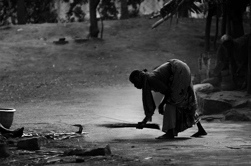 A woman in rural India cleaning the floor in front of their house, the light was mostly from behind the subject lighting up the dust and leaving her as an almost silhouette. 