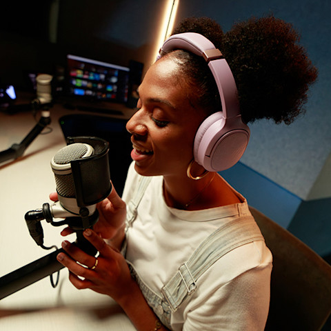 Smiling woman in a recording studio speaking into a microphone