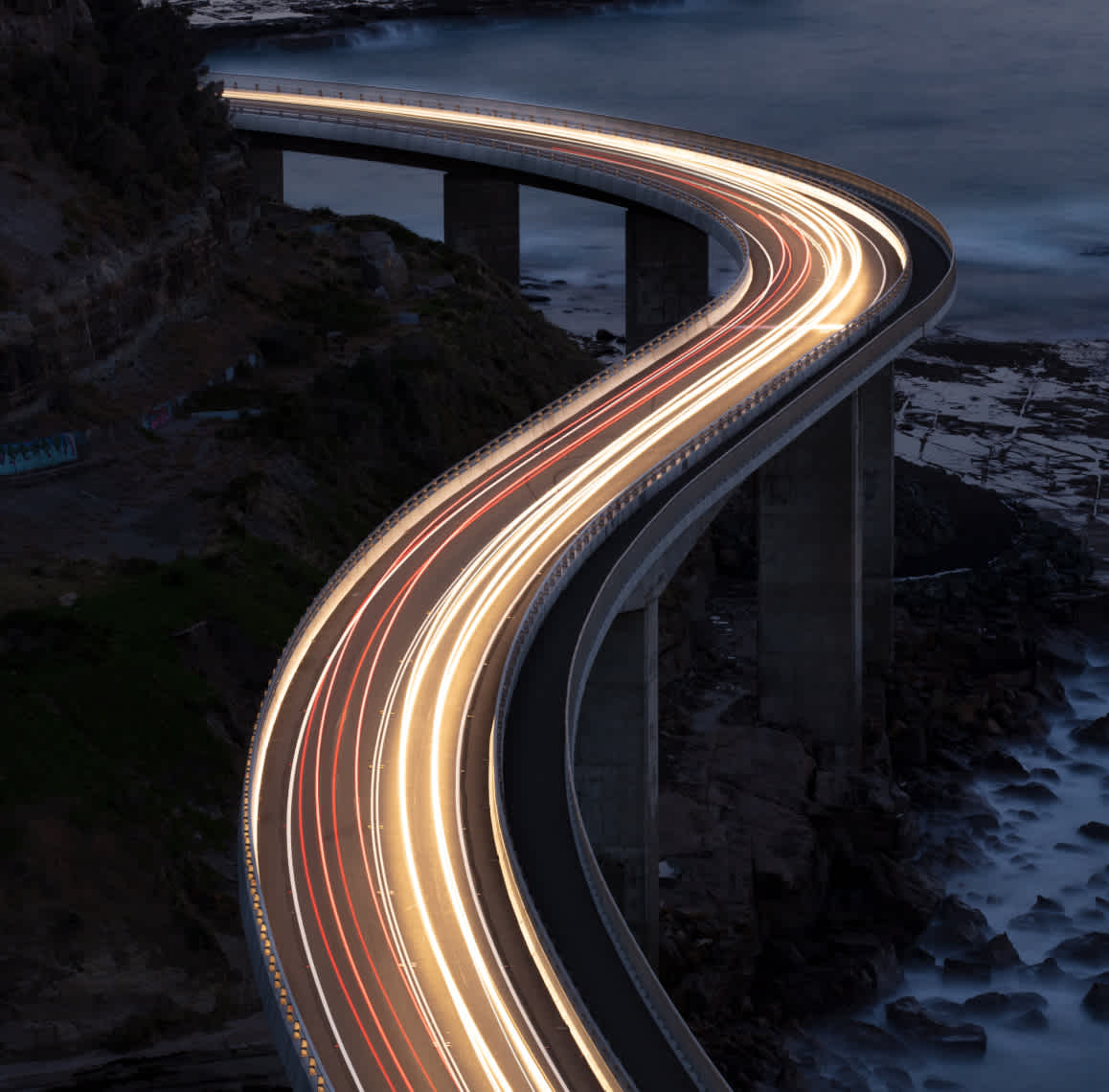 Car lights on an oceanside cliff captured with long-exposure