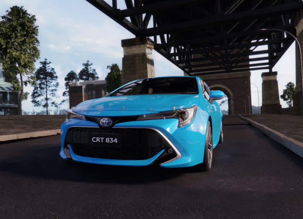 An aqua blue Toyota car driving on the street under a bridge.