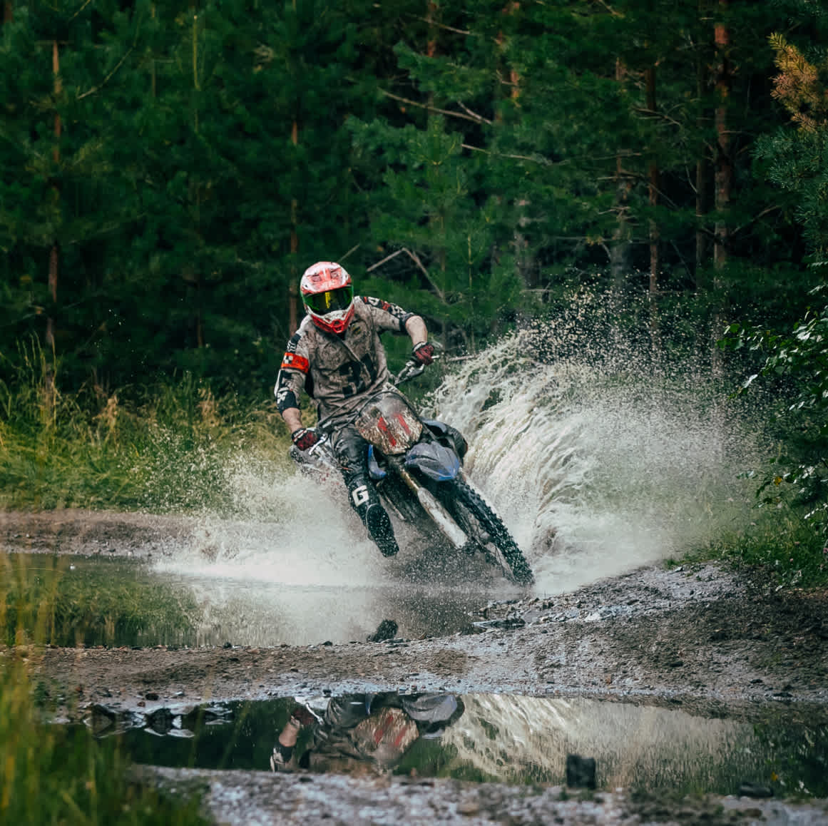 Person on dirtbike riding though a puddle in a forest