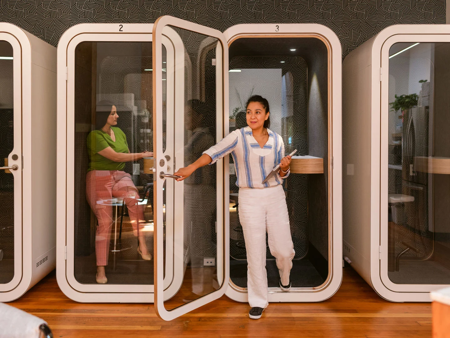Image of woman stepping out of small meeting booth