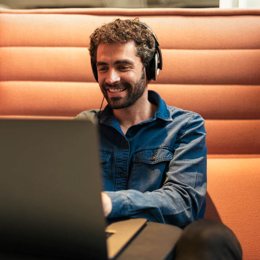 Image of man with headphones smiling while using laptop