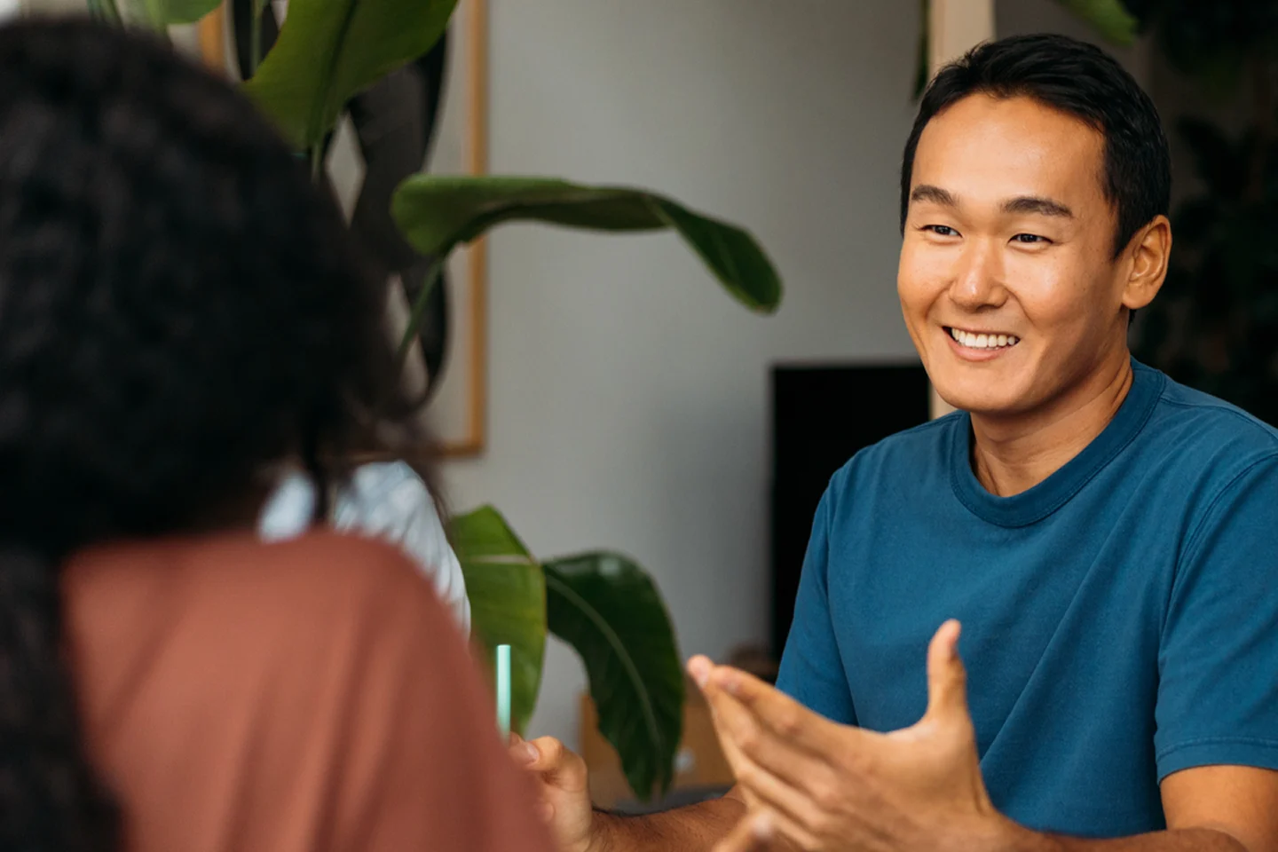Image of man smiling in front of desk of coworkers