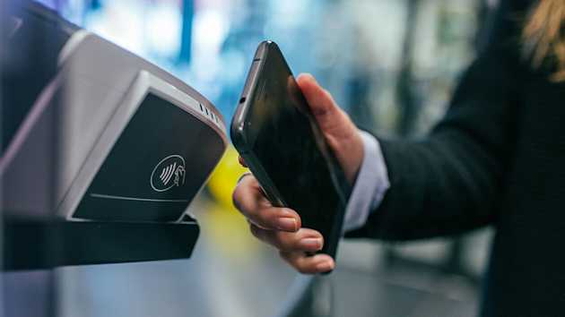woman holding smartphone using tap to pay contactless transaction
