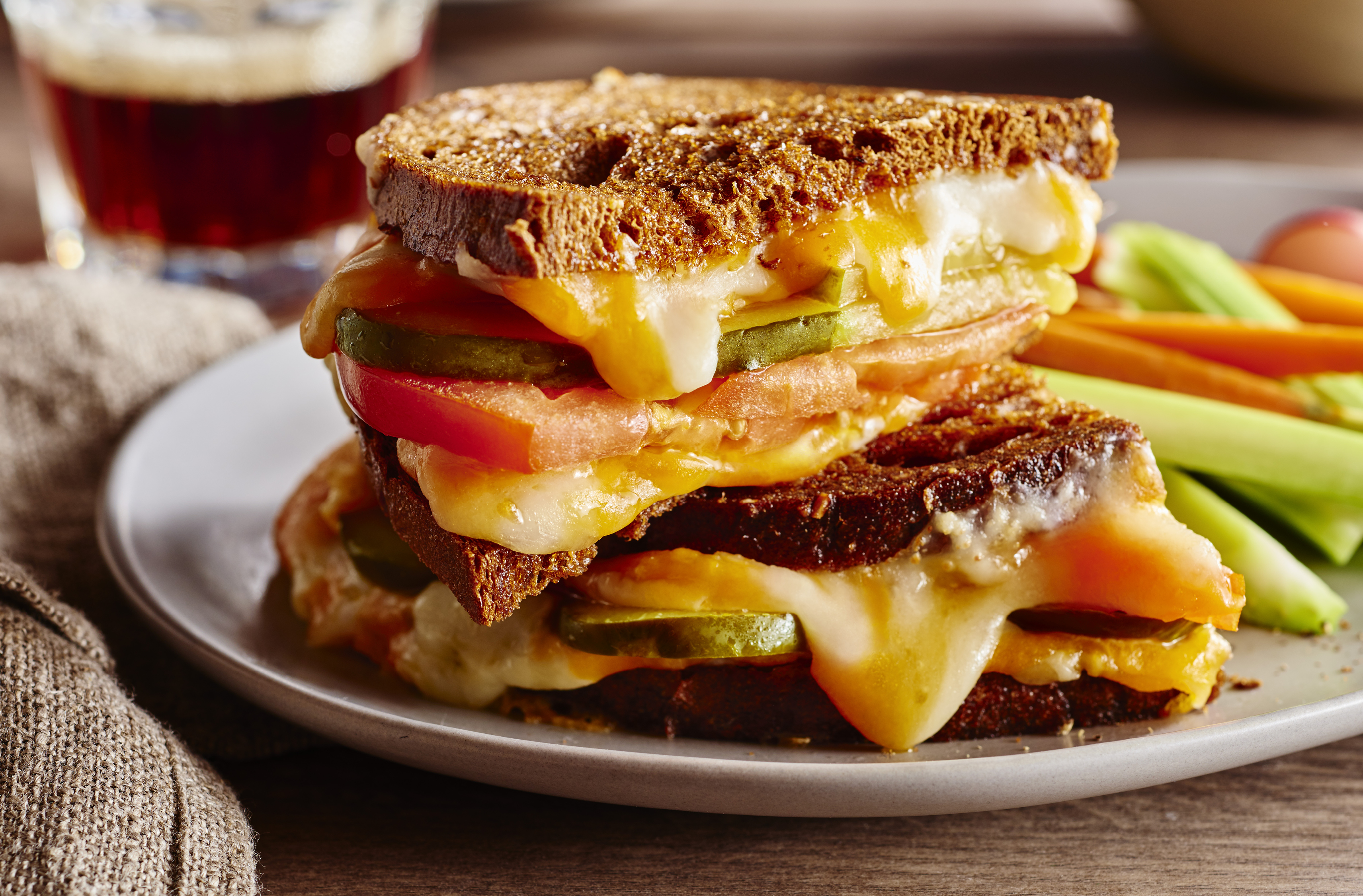 A double decker rye bread sandwich filled with melted lactose-free cheese and vegetables

