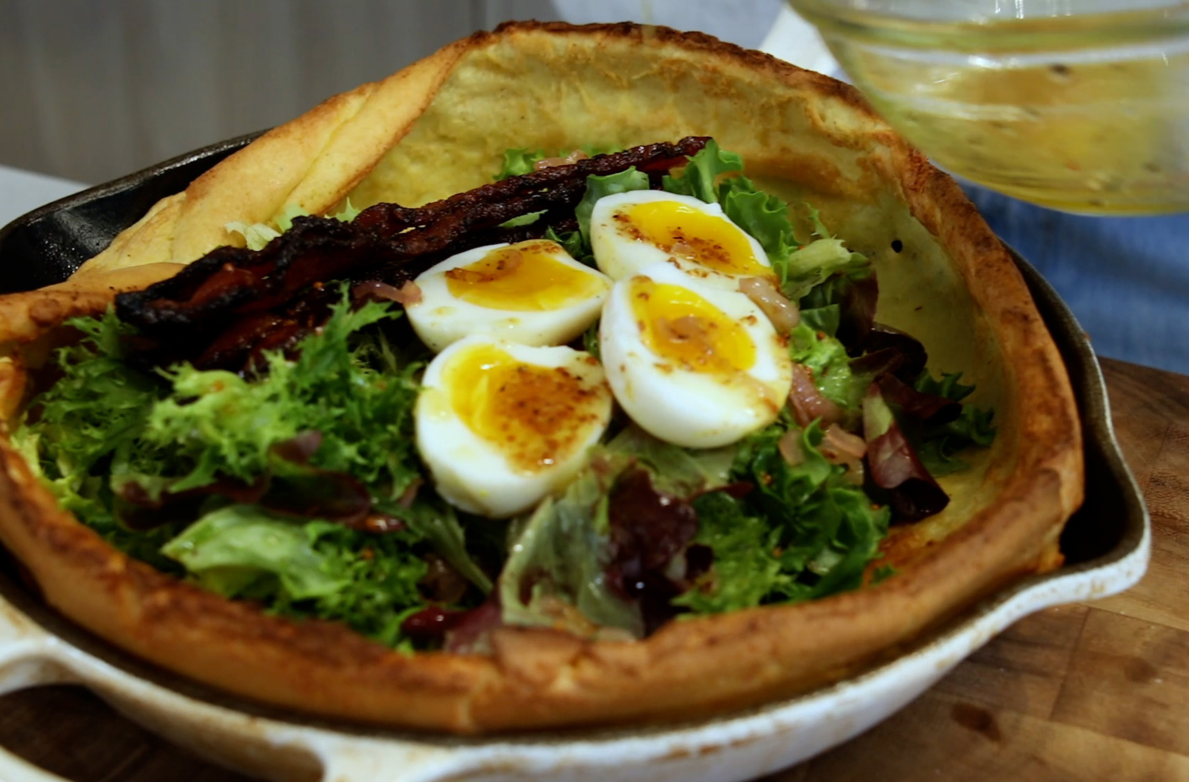 A large Dutch pot with a crisp toasted Dutch Baby filled with lettuce, bacon and eggs.